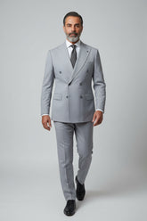 Man wearing light grey double-breasted suit with peak lapels and tailored fit.